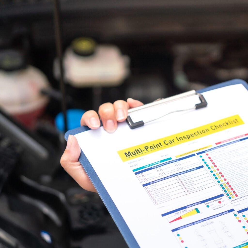Close-up at a mechanic foreman's hand is checking on multi-point car service guideline checklist form, to verify the car service quality. Expertise working action scene, selective focus.